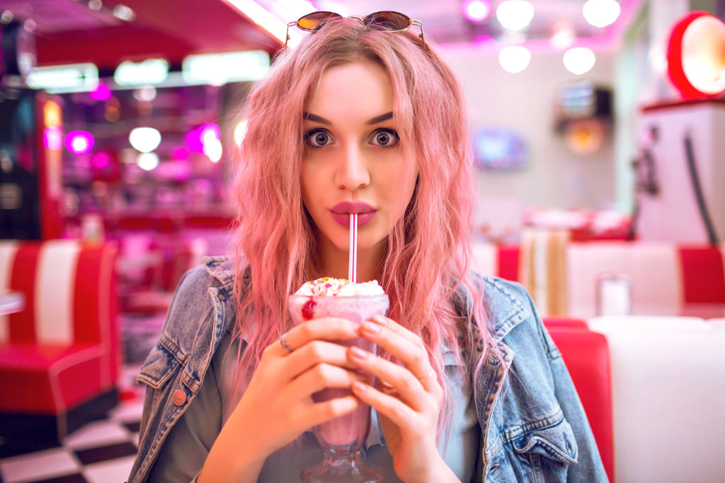 девушка с розовыми волосами пьет милкшейк